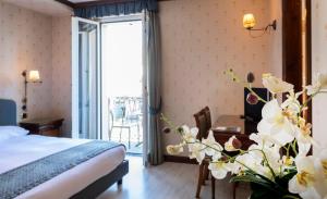 a hotel room with a bed and a table with flowers at Hotel Du Lac Menaggio in Menaggio
