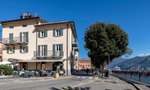 a building on the side of a street with a tree at Hotel Du Lac Menaggio in Menaggio