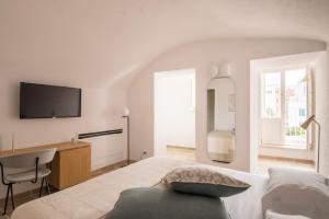 a white bedroom with a bed and a desk at Palazzo Mulini in Monopoli