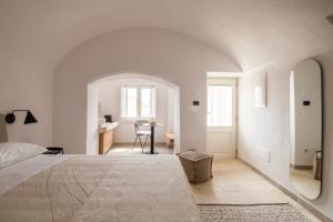a white bedroom with a bed and a mirror at Palazzo Mulini in Monopoli