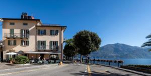 a building on the side of a road next to a lake at Hotel Du Lac Menaggio in Menaggio