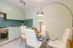 eine Küche mit einem Glastisch und weißen Stühlen in der Unterkunft Apartment Kalea in Dubrovnik