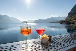two wine glasses sitting on a table next to the water at Hotel Du Lac Menaggio in Menaggio