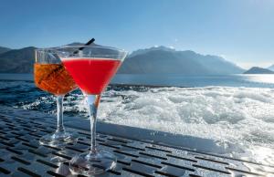 two wine glasses sitting on a table near the water at Hotel Du Lac Menaggio in Menaggio