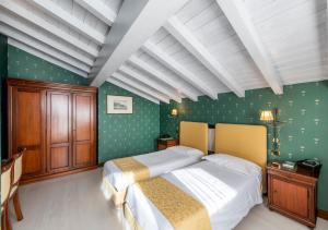 a bedroom with a large bed with green walls at Hotel Du Lac Menaggio in Menaggio