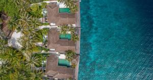 an aerial view of a resort with palm trees and water at Naladhu Private Island Maldives in South Male Atoll