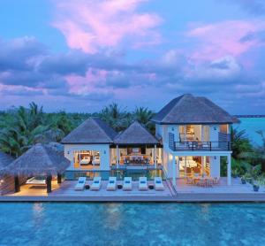 a villa in the middle of the water at dusk at Naladhu Private Island Maldives - Special Offer On Transfer Rates For Summer 2024 in South Male Atoll