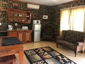 a kitchen with a refrigerator and a chair and a table at Monkey Mountain Family Lodge in Gemsbokfontein