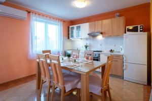 eine Küche mit einem Tisch und Stühlen sowie einem weißen Kühlschrank in der Unterkunft Kastell Apartments in Lopar