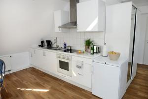 a white kitchen with white appliances and wooden floors at Ferienwohnungen im HOF68 in Münster