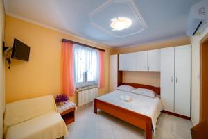 ein Schlafzimmer mit einem Bett, einem Fenster und einem Sofa in der Unterkunft Kastell Apartments in Lopar