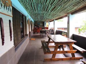 une terrasse avec une table en bois et des bancs dans un restaurant dans l'établissement Bushpigs Haven, à St Lucia