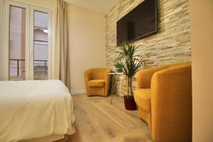 een slaapkamer met een bed en twee stoelen en een televisie bij A Loft You Will Fall In Love With in Tarragona