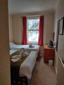 Duas camas num pequeno quarto com uma janela em Inglewood Palm Hotel, Abbey Sands Torquay em Torquay