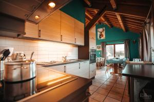een keuken met groene muren, houten kasten en een tafel bij Le Brocard des Fagnes - 16 pers Malmedy in Malmedy