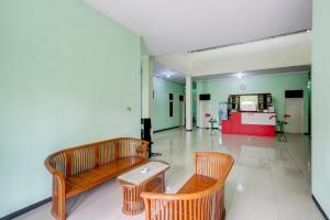 uma sala de estar com dois bancos e uma mesa em Capital O 90709 Djati Guest House em Kudus