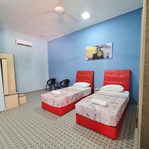 Kampung RajaにあるD'EMBUN INAP DESA BESUTの青い壁の客室で、ベッド2台、赤い椅子が備わります。