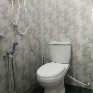 een badkamer met een toilet met een slang aan de muur bij D'EMBUN INAP DESA BESUT in Kampung Raja