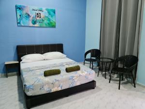 a bedroom with a bed with blue walls and chairs at D'EMBUN INAP DESA BESUT in Kampung Raja