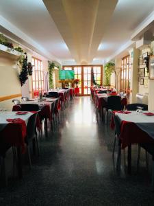 une rangée de tables dans un restaurant avec des nappes rouges dans l'établissement Hotel Centrale, à Quartu SantʼElena