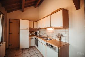 a kitchen with white cabinets and a white refrigerator at La Trientale 10 pers -Malmedy in Xhoffraix +17 photos