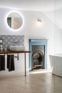une salle de bain avec une baignoire et un lavabo et une cheminée dans l'établissement Cusgarne Manor boutique B&B - adults only, à Cusgarne