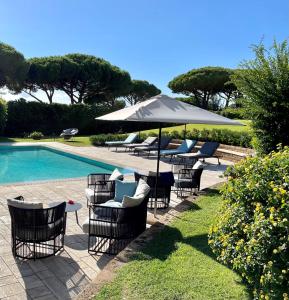 a group of chairs and an umbrella next to a pool at Gallia Palace Hotel - Relais & Ch&acirc;teaux in Punta Ala