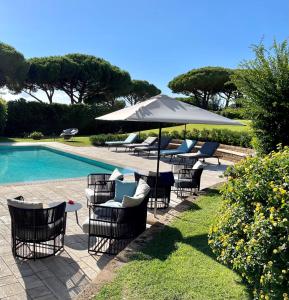 um grupo de cadeiras e um guarda-sol junto a uma piscina em Gallia Palace Hotel - Relais & Châteaux em Punta Ala