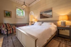 1 dormitorio con 1 cama blanca grande y 1 silla en Stunning luxury cottage in historic country estate - Belchamp Hall Stables, en Belchamp Otten