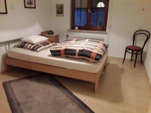 a bed with two pillows and a chair in a room at Feriendomizil Berta Benzingen in Winterlingen