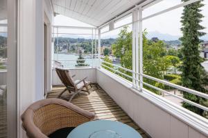 a balcony with chairs and a table and windows at Seehotel Hubertushof in Velden am Wörthersee