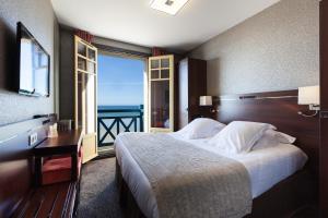 a bedroom with a bed and a view of the ocean at Ambassadeurs Logis Hotel in Saint Malo