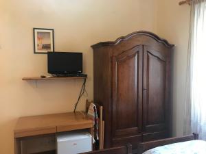 a bedroom with a wooden cabinet and a television at Affittacamere Cerisola 2003 in Zoagli