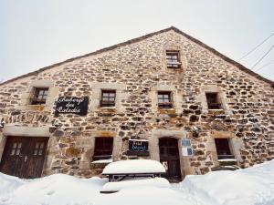 a stone building with snow in front of it at Auberge des Calades in Les Estables