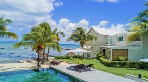 a house with a swimming pool next to the ocean at White Oaks Villas in Trou aux Biches