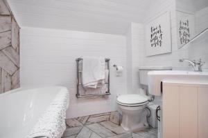 baño blanco con bañera, aseo y lavamanos en Luxury lodge in the heart of the Cotswolds, en Cirencester