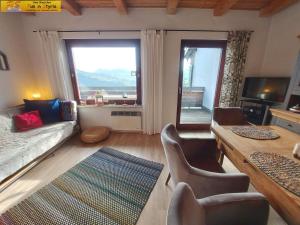 uma sala de estar com um sofá, cadeiras e janelas em Ferienwohnung Montania by FiS - Fun in Styria em Tauplitz