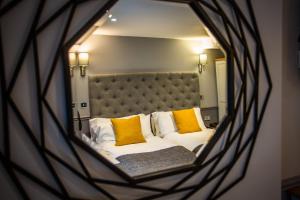 a reflection of a bed with yellow pillows in a mirror at Kinloch Hotel, Isle of Arran in Blackwaterfoot