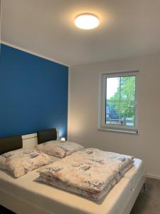 a bedroom with a bed with a blue wall and a window at "Ostsee Ankerplatz" in Markgrafenheide
