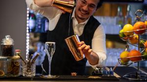 Een man maakt een drankje in een bar. bij Hotel La Chaumiere in Asse