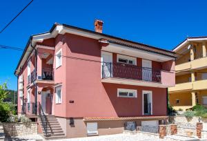 un bâtiment rose avec des escaliers et un balcon. dans l'établissement Mistral Apartments, à Lopar