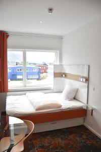 Ce lit se trouve dans un dortoir doté d'une grande fenêtre. dans l'établissement HHE Express, à Nuuk