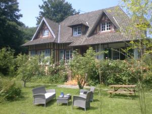 a house with chairs and a picnic table in the yard at Moulin du Hamelet in Saint-Aubin-sur-Scie