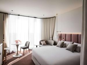 a hotel room with a large bed and a table at Hotel Chadstone Melbourne, MGallery by Sofitel in Chadstone