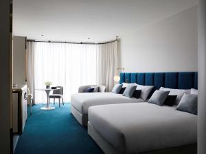 查斯顿Hotel Chadstone Melbourne MGallery Collection的有两张床和一张桌子的酒店房间