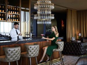 a woman in a green dress sitting at a bar at Hotel Chadstone Melbourne, MGallery by Sofitel in Chadstone