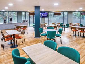 a dining room with tables and chairs and windows at ibis budget London Heathrow Terminal 5 in Slough