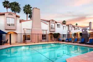 - une piscine en face d'un bâtiment avec des palmiers dans l'établissement Sonesta ES Suites Scottsdale Paradise Valley, à Scottsdale