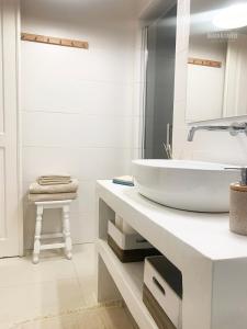 a white bathroom with a sink and a stool at Beach & Castle - Sines Apartment in Sines
