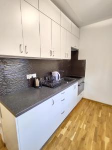 a kitchen with white cabinets and a wooden floor at Apartament pod Zamkiem in Nowy Sącz